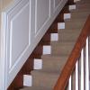 The wainscoting staircase panel ends just prior to the corner of the wall and the 3 1/4" top cap is mitered to go vertical along the panel edge.