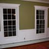 Raised Panel Dining Room photo in Blauvelt, NY.  The wainscot is installed above a hot water baseboard radiator.  The windows have fluted pilasters with pediment heads and the plinth blocks sit on the baseboard radiator. 